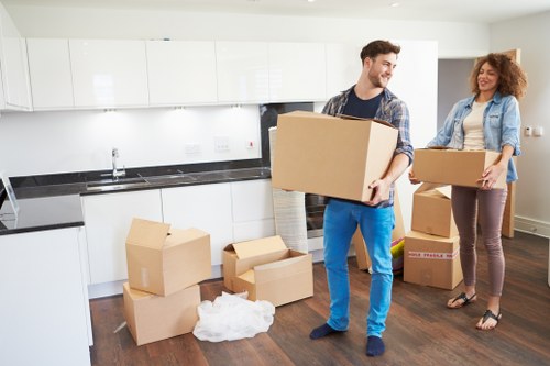 Movers carrying boxed household items through a narrow hallway