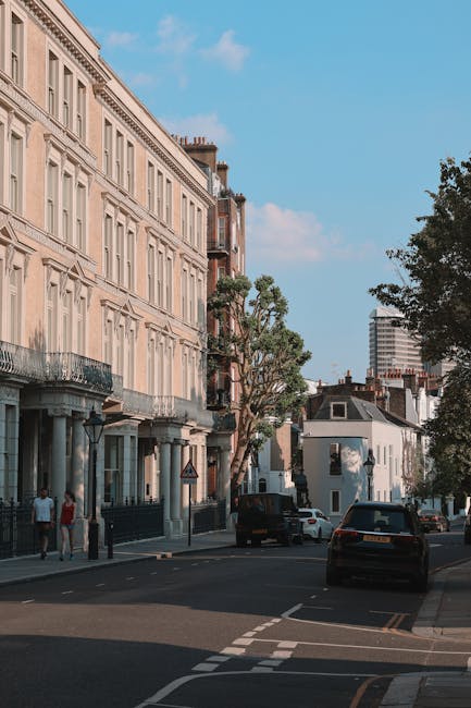 A street scene depicting a row of multi-story residential and commercial buildings in Upper Clapton under a partly cloudy sky. The buildings are constructed with red brick and beige materials, some fe